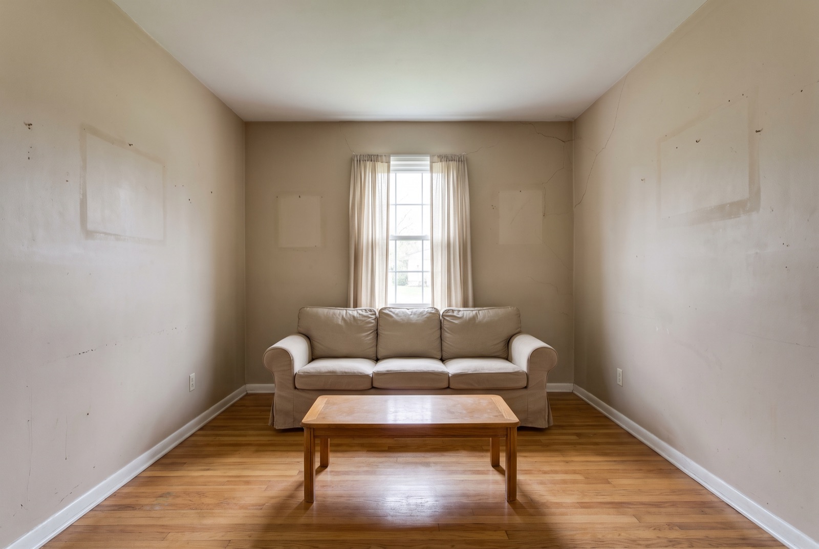 Living room before painting: tired beige walls with scuffs and patch marks